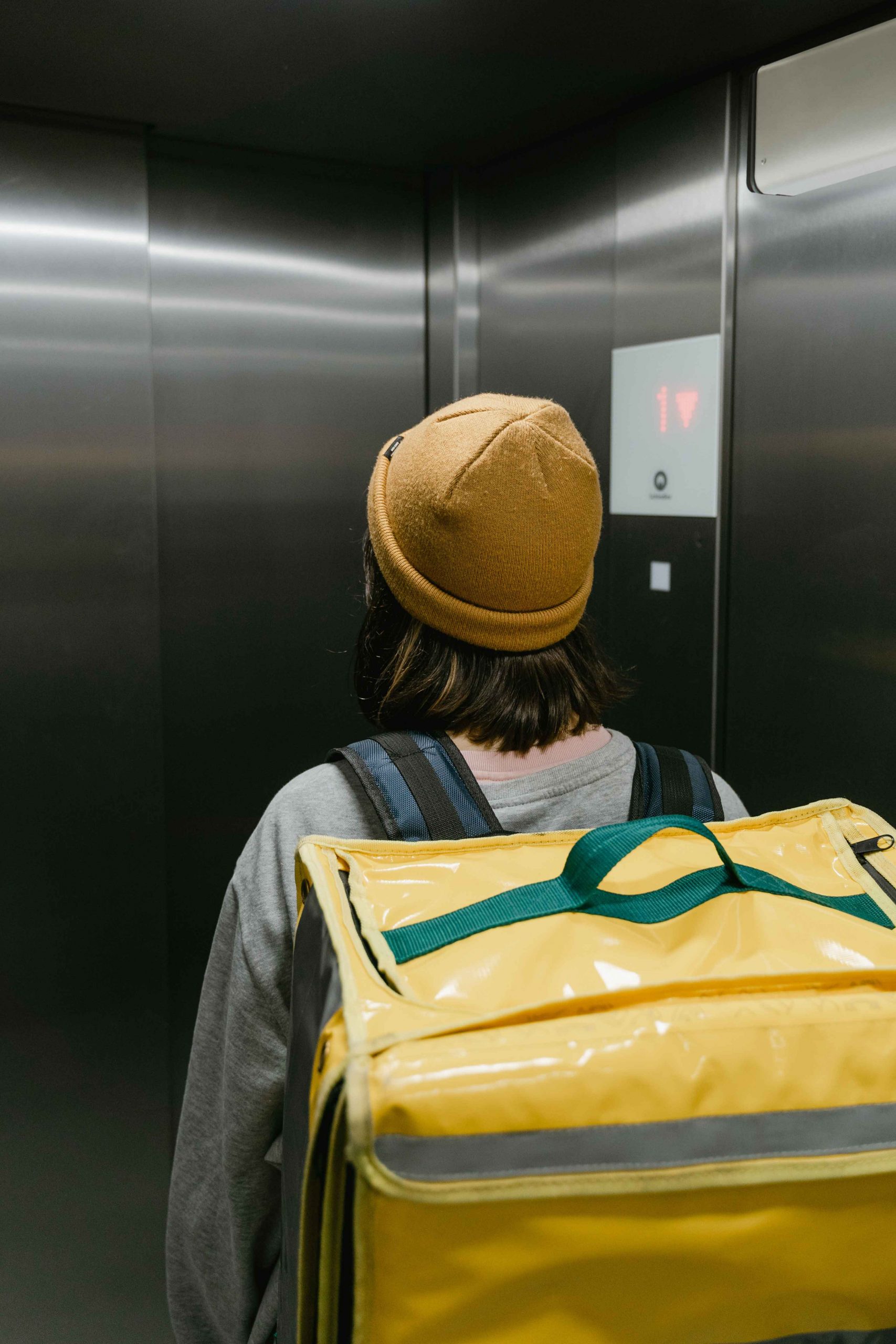 Person in Aufzug mit gelber Tasche